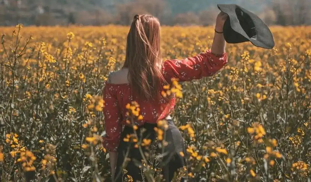 Woman in floral shirt holding hat.