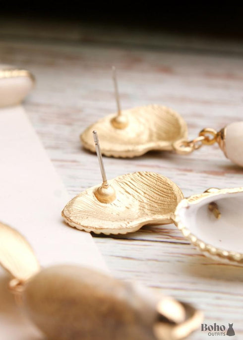 Pendientes bohemios colgantes de concha natural y cauri en oro blanco.