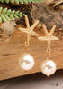 Pendientes bohemios colgantes de concha de estrella de mar y cauri en oro blanco.