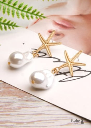 Pendientes bohemios colgantes de concha de estrella de mar y cauri en oro blanco.