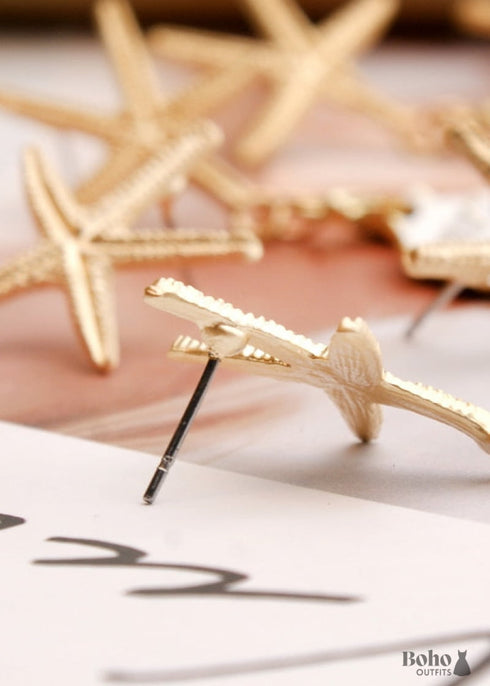 Pendientes bohemios colgantes de concha de estrella de mar y cauri en oro blanco.