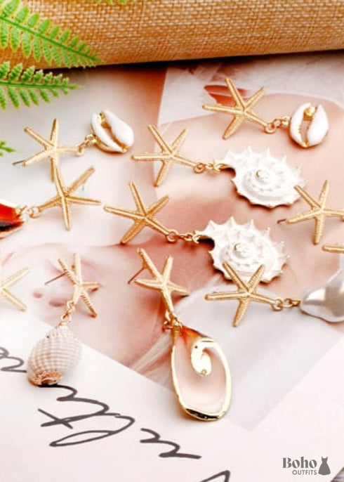 Pendientes bohemios colgantes de concha de estrella de mar y cauri en oro blanco.