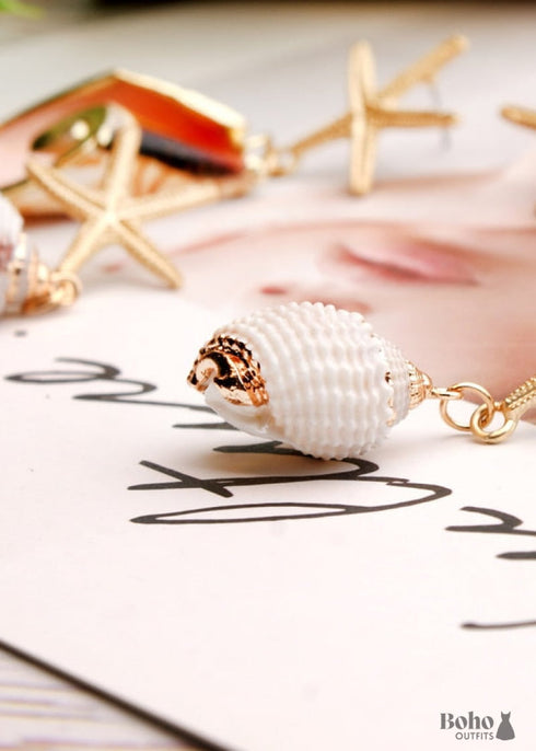 Pendientes bohemios colgantes de concha de estrella de mar y cauri en oro blanco.